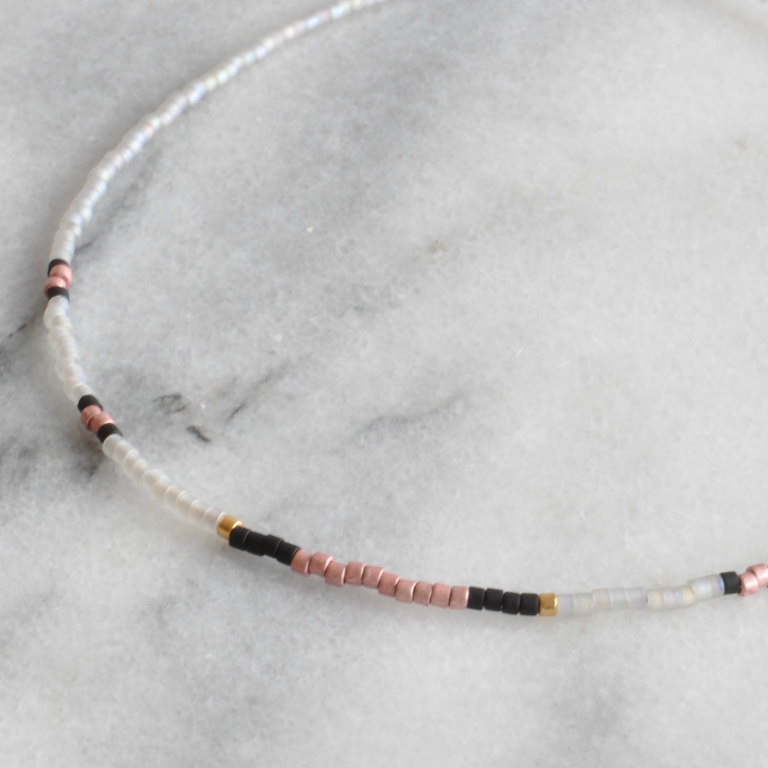 Close up of Libby & Smee grey beaded choker necklace with pale grey, metallic pink, matte black and gold beads
