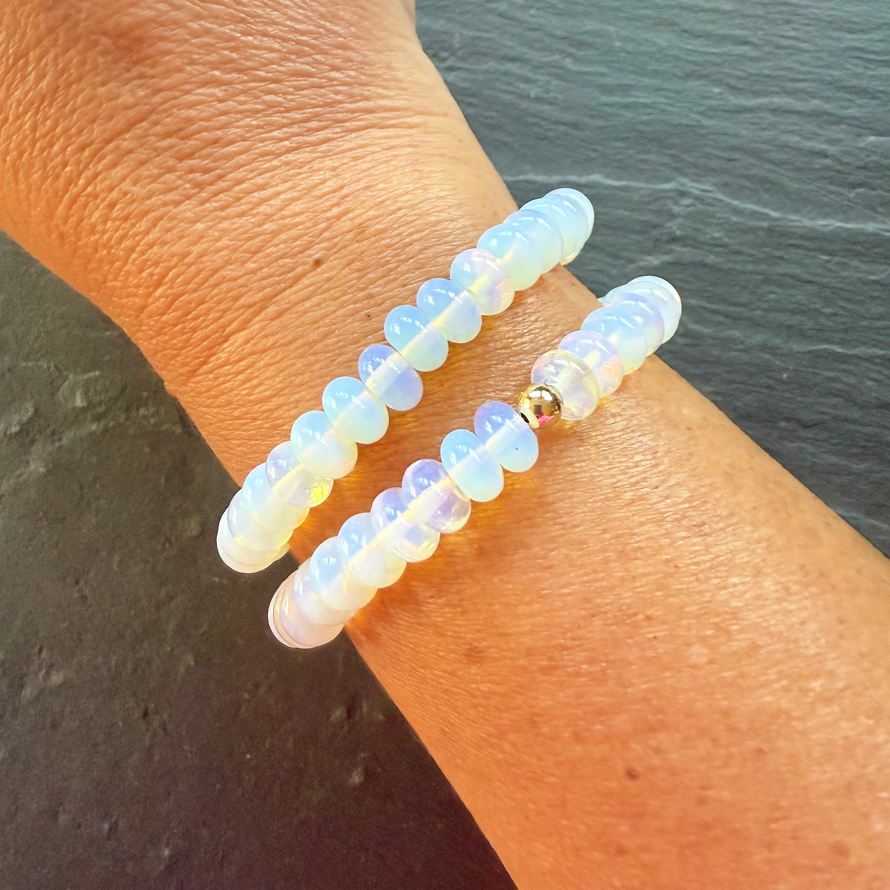 Two beaded bracelets on a wrist with a dark background