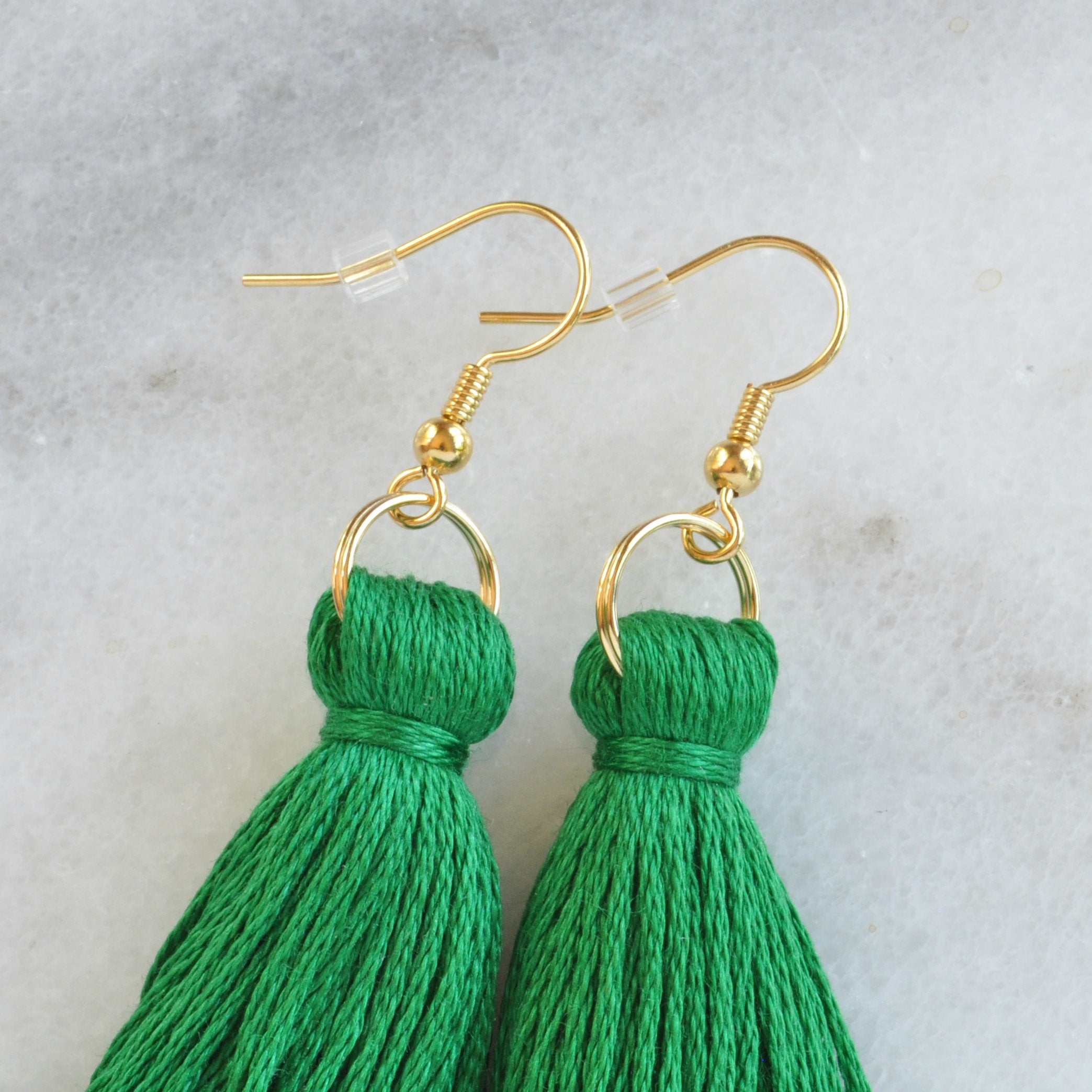 Close up of Emerald Green tassel earrings from Libby & Smee with a plastic earring backing