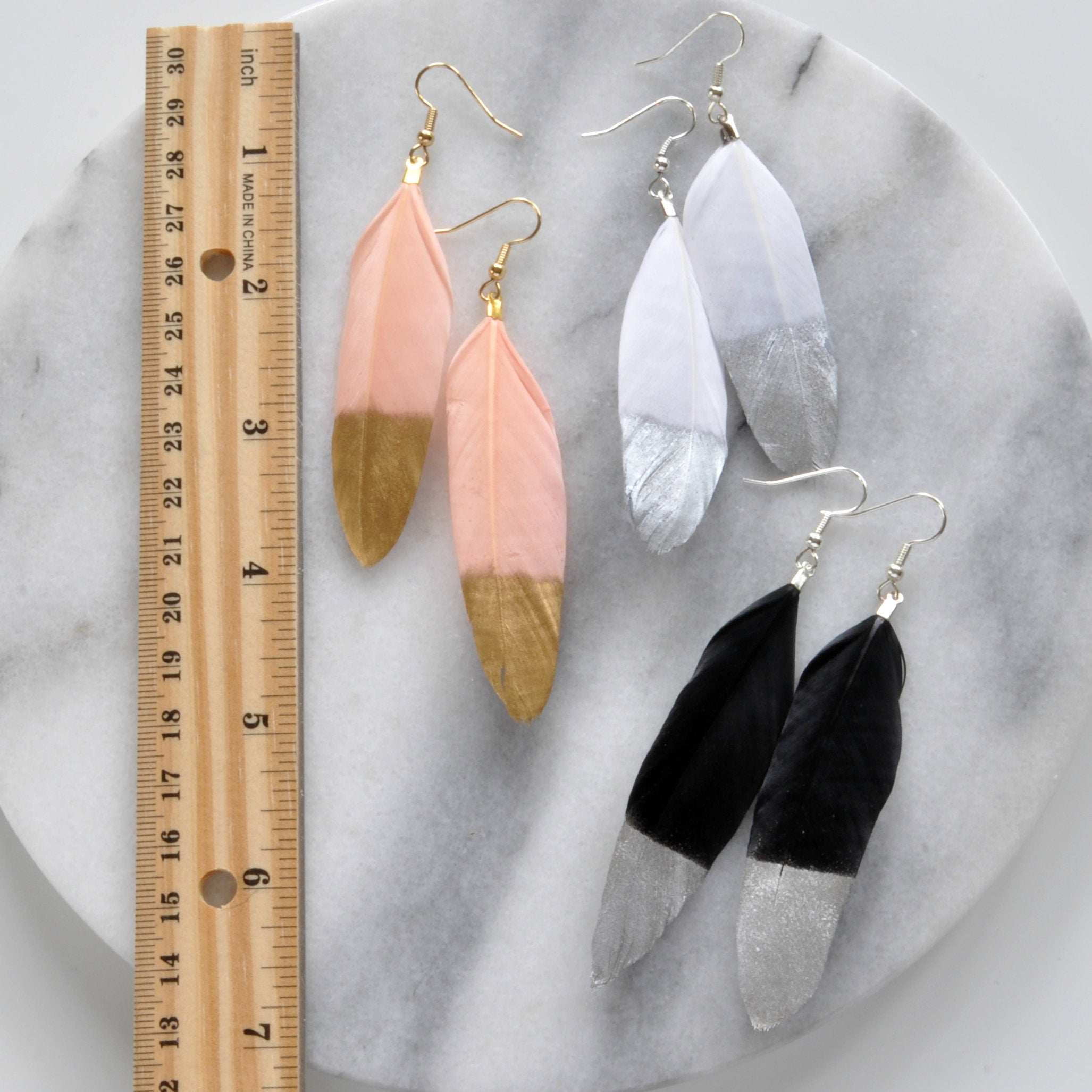 Libby & Smee Gold and Silver Feather Earrings in blush with gold, white with silver, black with silver, still life with ruler