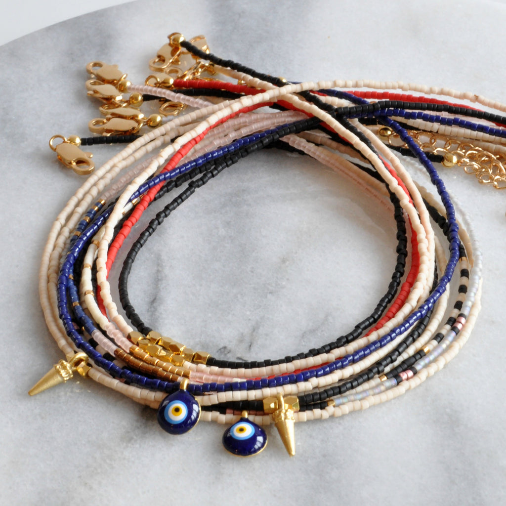 Libby & Smee beaded choker necklaces with small seed beads, gold spike accents and evil eye charms