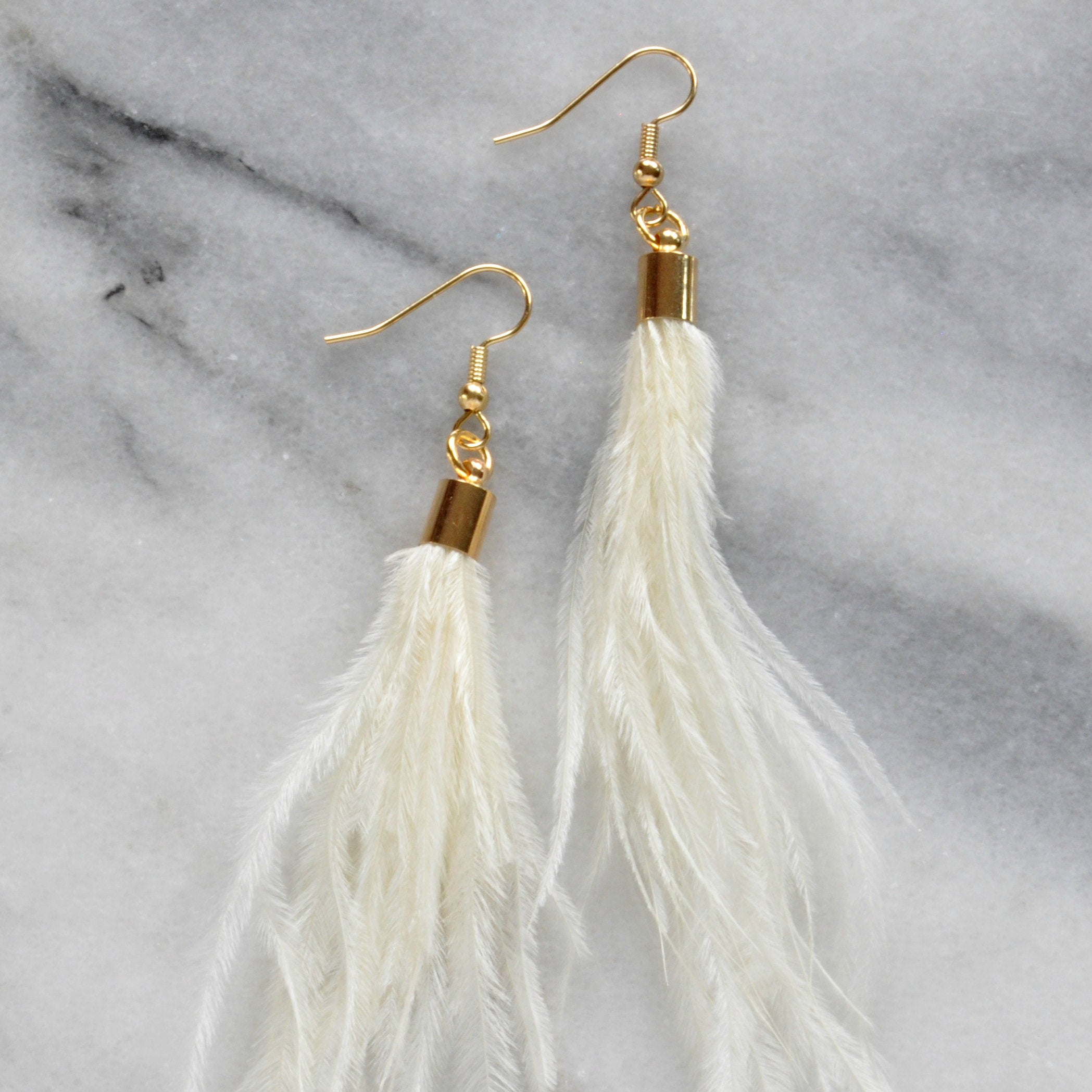 Libby & Smee ivory ostrich feather earrings with gold cap, still life on kraft logo earring card